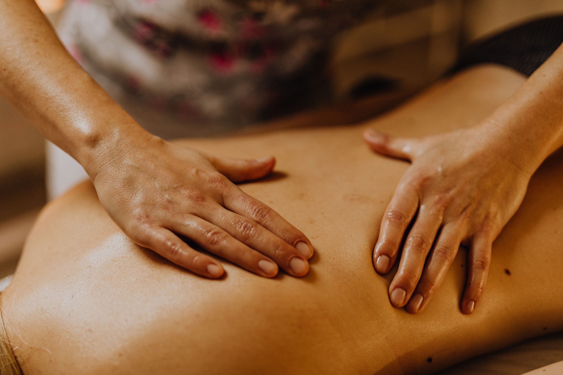 Zwei Hände liegen bei einer Massage ruhig auf einem Rücken